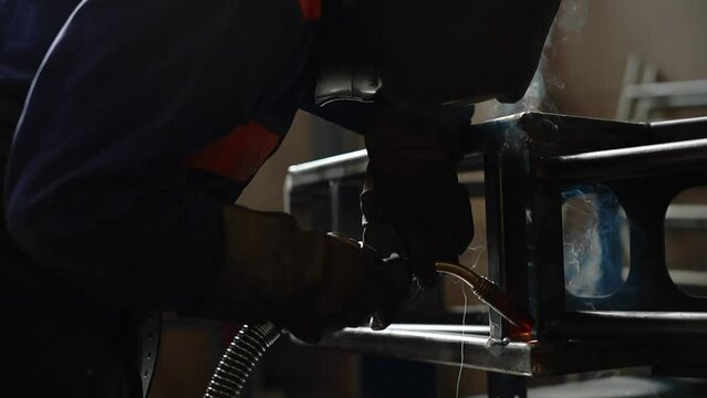 Skillful metal worker working with arc welding machine in factory while wearing safety equipment. Metalwork manufacturing and construction maintenance service by manual skill labor concept