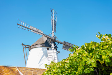 European old windmill, rural landscape, tiled roof, blue sky.