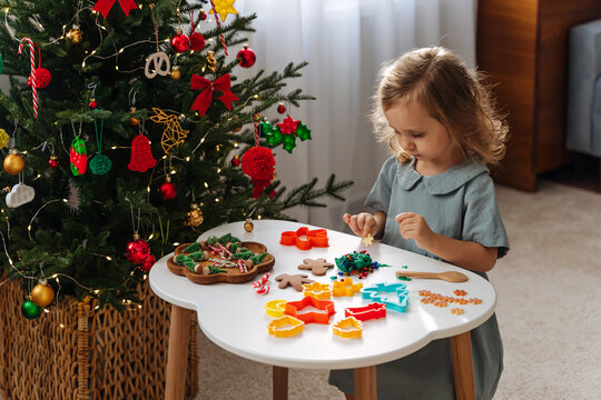 A little girl playing with play dough, plasticine and Christmas decorations. Child hands creating Christmas crafts. Holiday Art Activity for Kids. Sensory play for toddlers..