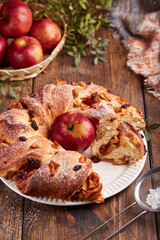 Yeast dough wreath pie with apples, cinnamon and raisins covered with sugar powder. Braided ring...