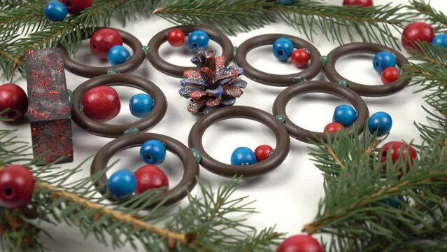 Handmade Christmas tree made of wooden rings and beads, branches of fresh spruce are on a white board, vintage background. Improvised materials for making craft, holidays concept