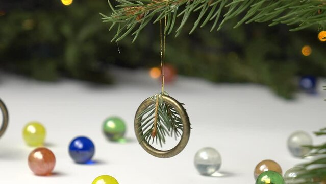 Handmade Christmas decoration from brass ring and spruce twig on the spruce branch against the background of spruce tree with Christmas lights, holiday concept.