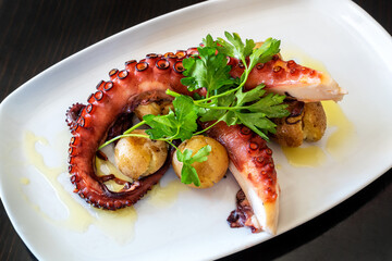 Boiled octopus tentacles according to a Mediterranean recipe with potatoes and parsley.