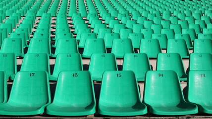 fragment of a stadium tribune with rows of green plastic chairs without people, like a city...