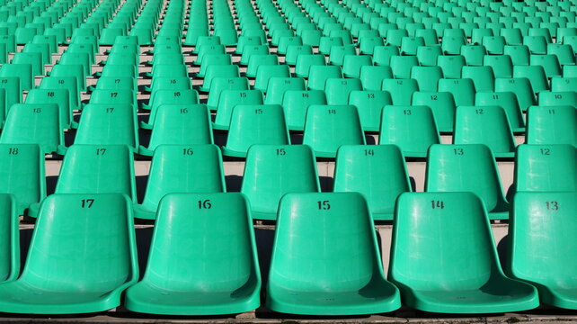 fragment of a stadium tribune with rows of green plastic chairs without people, like a city background, unoccupied seats for fans in the sector for watching sports competitions, city infrastructure