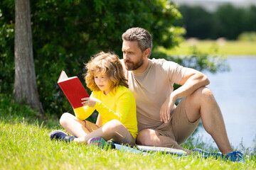 Outdoor school. Father and son reading book in park, man encourages boy to knowledge, family...
