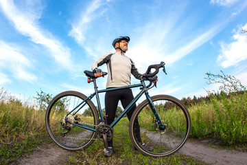 Bearded male cyclist is resting with a bike on the road in nature. cycling and health hobbies