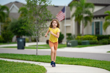 Kid running in summer street. Child enjoy run. Little boy running on neighborhood street. Kids run on american city running road. Child boy running in park. Sports and fitness, run exercise for kids.