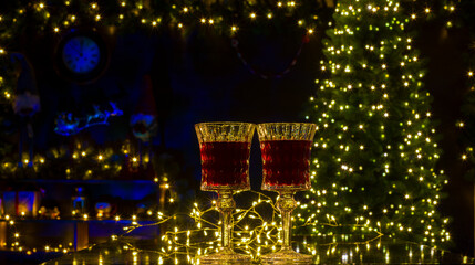 two glasses with red wine on a background of christmas decoration.christmas background banner with glasses of drink and christmas lights