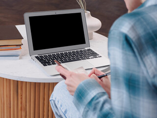 Young woman using laptop and sitting on couch at home. Beautiful girl shopping or chatting online...