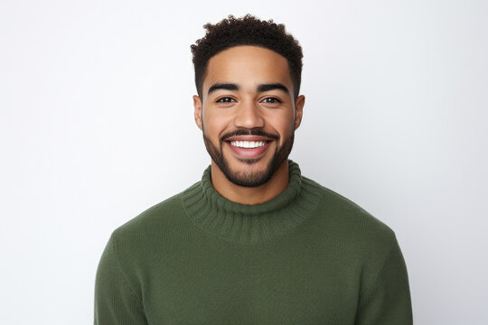 Man wearing green sweater smiles directly at camera. This image can be used to convey friendliness and approachability.