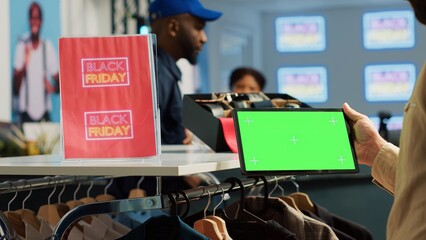 Male client on black friday with greenscreen tablet, holding isolated display device and looking at...