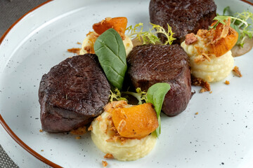 Small steaks garnished with greens. Some mashed potatoes. Macro