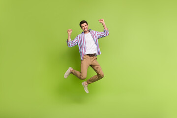 Fototapeta na wymiar Full size body photo of crazy active youngster man jumping raised fists up big discount promo shopping isolated on green color background