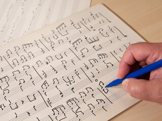 writing a piano score with a felt-tip pen on a table along with other compositions