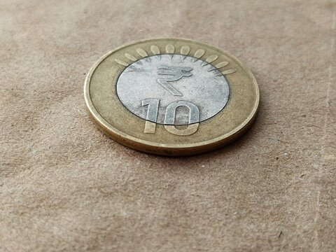 Indian close up of currency ten rupees coin isolated on wheatish background.
