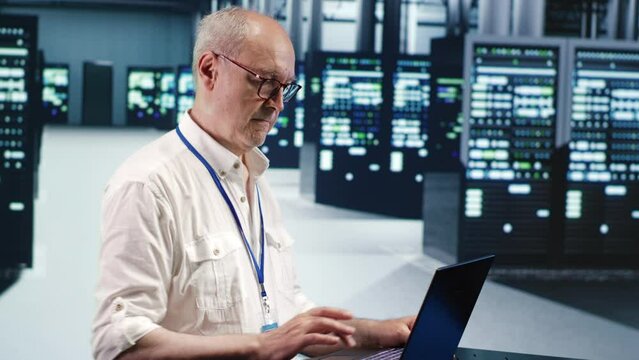 Competent inspector expertly managing data while navigating in industrial server room. Experienced system administrator ensuring optimal cybersecurity protection, optimizing systems