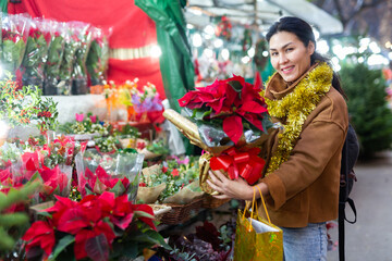 Portrait of smiling asian woman with christmas flower poinsettia at christmas market outdoors