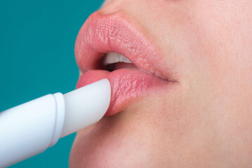 Applying lipstick om plump sexy lips. Painting lips with bright lipstick, close up. Pampering, lips correction concept. Glossy lipstick on full plump sensual lip. Woman hand applying lipstick.