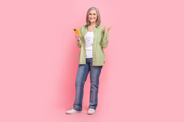 Naklejka premium Photo of satisfied cheerful pensioner wear stylish clothes recommend buy modern technology empty space isolated on pink color background