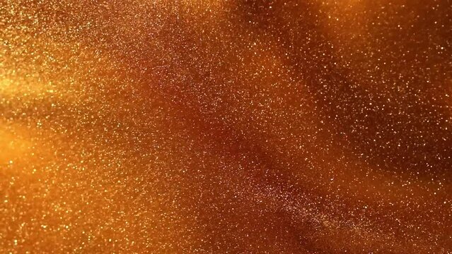 Gold liquid with tints of golden glitters. Yellow background with a scattering of gold sparkles. Magic Galaxy of golden dust particles in fluid. 