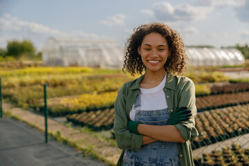 Smiling female agronomist standing on the field on greenhouses background. High quality photo