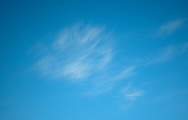 Blue sky with fluffy white clouds moved by the wind in horizontal background