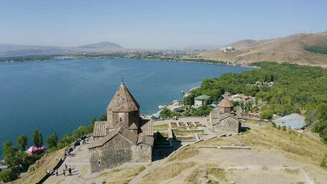 Backward reveal drone shot of Sevanavank monastery on sunny summer day. Sevan Lake, Armenia.