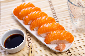 Sake nigiri - tasty dietary sushi with salmon and tuna, soy sauce closeup