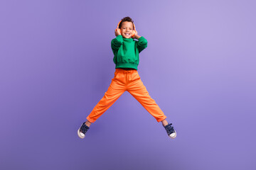 Fototapeta na wymiar Photo of cheerful nice boy wear stylish green outfit listen mp3 player wireless device isolated on purple color background