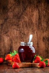 Homemade strawberry jam or confiture in glass jar and fresh berries, rustic wooden table background, copy space