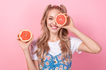 Photo of lovely optimistic cute woman with tails hairdo dressed print overall grapefruit cover eye isolated on pink color background