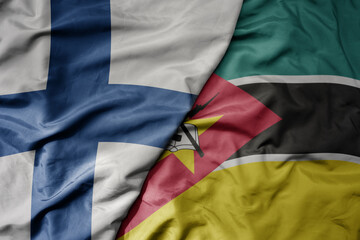 big waving national colorful flag of finland and national flag of mozambique .