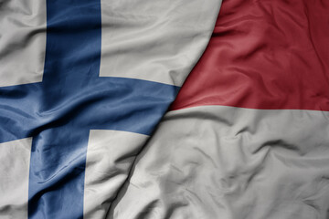 big waving national colorful flag of finland and national flag of indonesia .