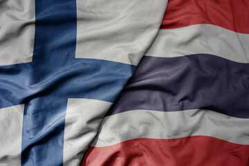 big waving national colorful flag of finland and national flag of thailand .