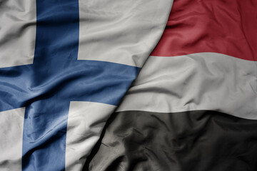 big waving national colorful flag of finland and national flag of yemen .