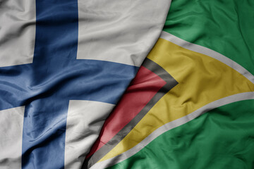 Obraz premium big waving national colorful flag of finland and national flag of guyana .