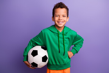 Photo of positive good mood small boy wear green sweatshirt enjoying playing football isolated violet color background
