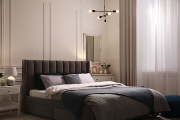Stylish bedroom interior with large comfortable bed and table