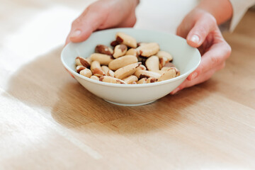 Brazil nuts in the diet. Healthy fats in the diet. Brazil nuts in a white ceramic cup in hand on a wooden table.Nuts and seeds.Useful healthy snack. 