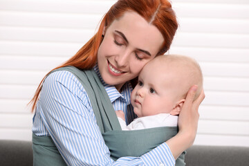 Mother holding her child in sling (baby carrier) indoors