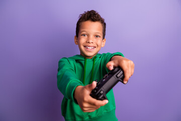 Photo of excited funky small boy wear green sweatshirt enjoying playing playstation isolated violet color background © deagreez