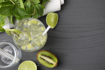 Glass of refreshing drink with kiwi and ingredients on gray wooden table, flat lay. Space for text
