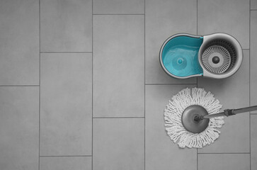 String mop and bucket on grey tiled floor, top view. Space for text