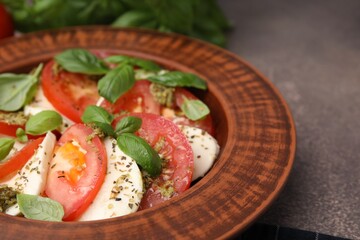 Plate of delicious Caprese salad with pesto sauce on brown textured table, closeup. Space for text