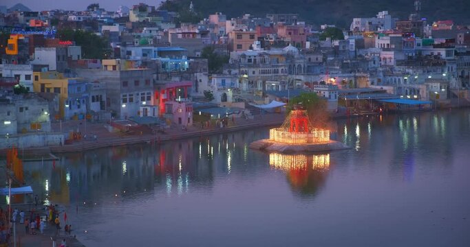 View of famous indian hinduism pilgrimage town sacred holy hindu religious city Pushkar with Brahma temple, aarti ceremony, lake and ghats illuminated at sunset. Rajasthan, India, Asia