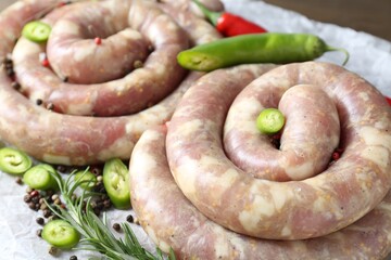 Homemade sausages, rosemary, chili and spices on table, closeup