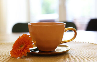 Cup of delicious chamomile tea and fresh calendula flower on table in room, closeup