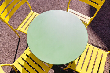 Green bistro table with yellow chairs, seen from above