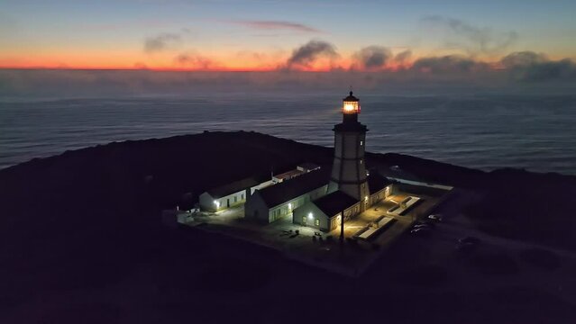 Aerial drone view of farol lighthouse on Cabo Espichel cape Espichel on Atlantic ocean in the evening. Sesimbra, Portugal. Orbit parallax shot
